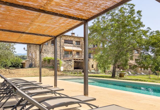 Shaded lounge chairs by the pool at a Country House with Private pool in La Garrotxa.