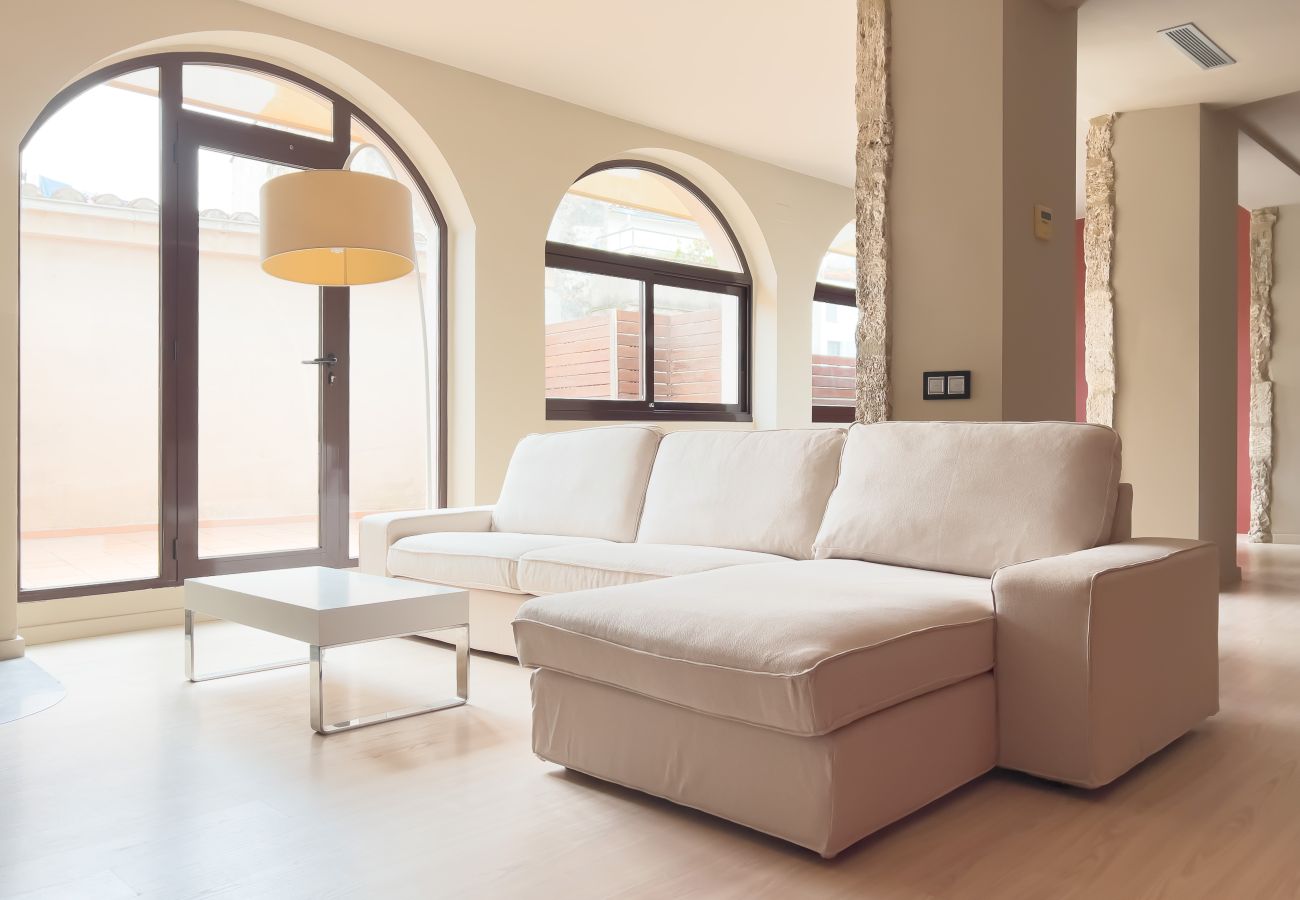 Bright living room in Banyoles with a beige corner sofa, modern coffee table, and large windows with arched frames.