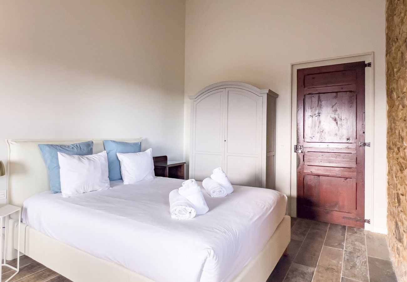 Double bedroom in a tower with exposed stone wall and antique wooden door in a Girona castle