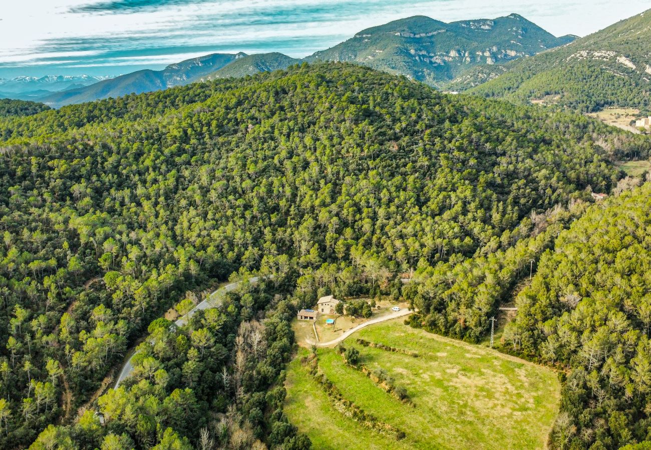 Vista lejana de la casa de piedra y montañas en Rural holiday home El Molí in La Garrotxa