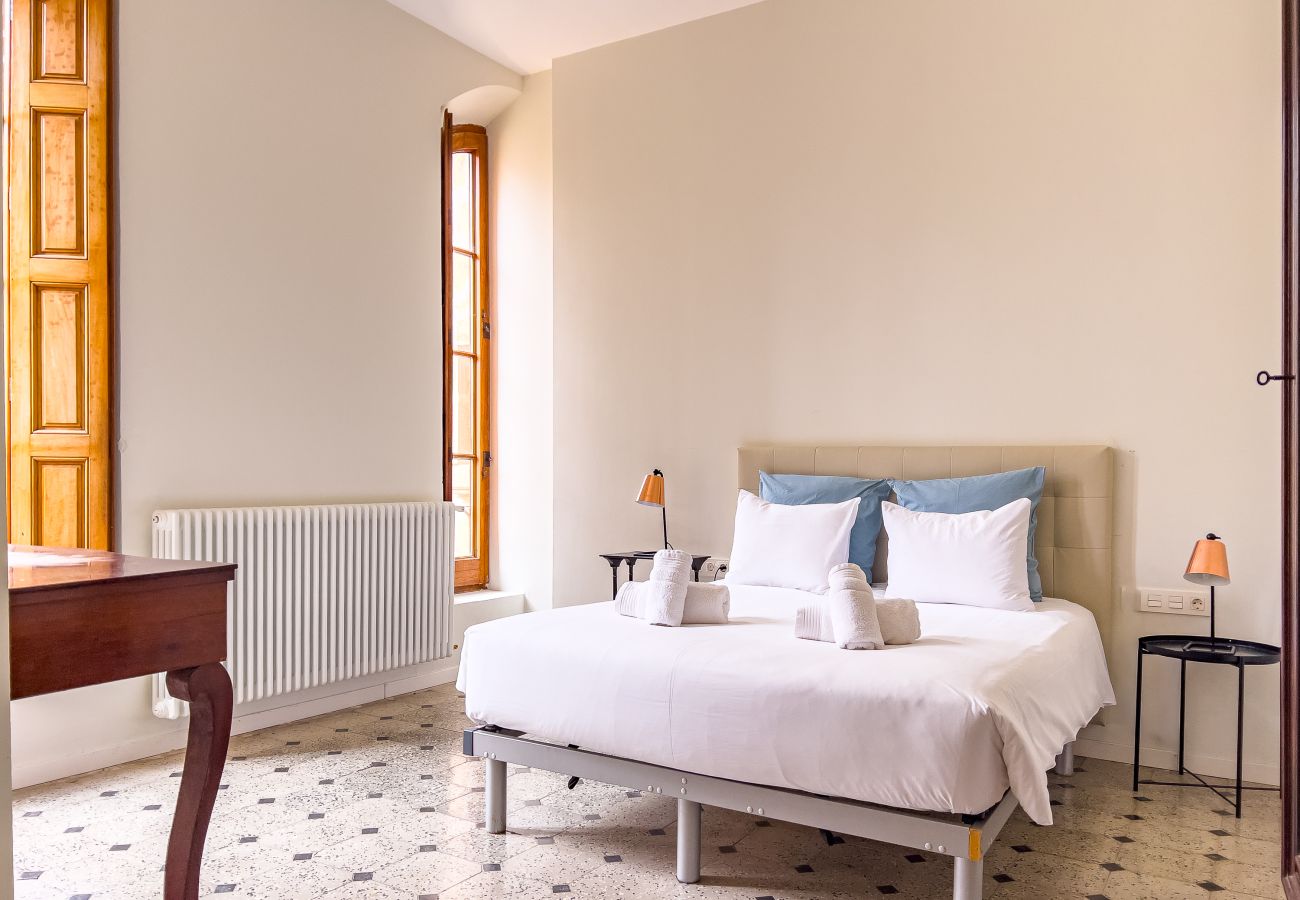 Habitación doble con ventanal arqueado y vistas a las copas de los árboles en un castillo de Girona