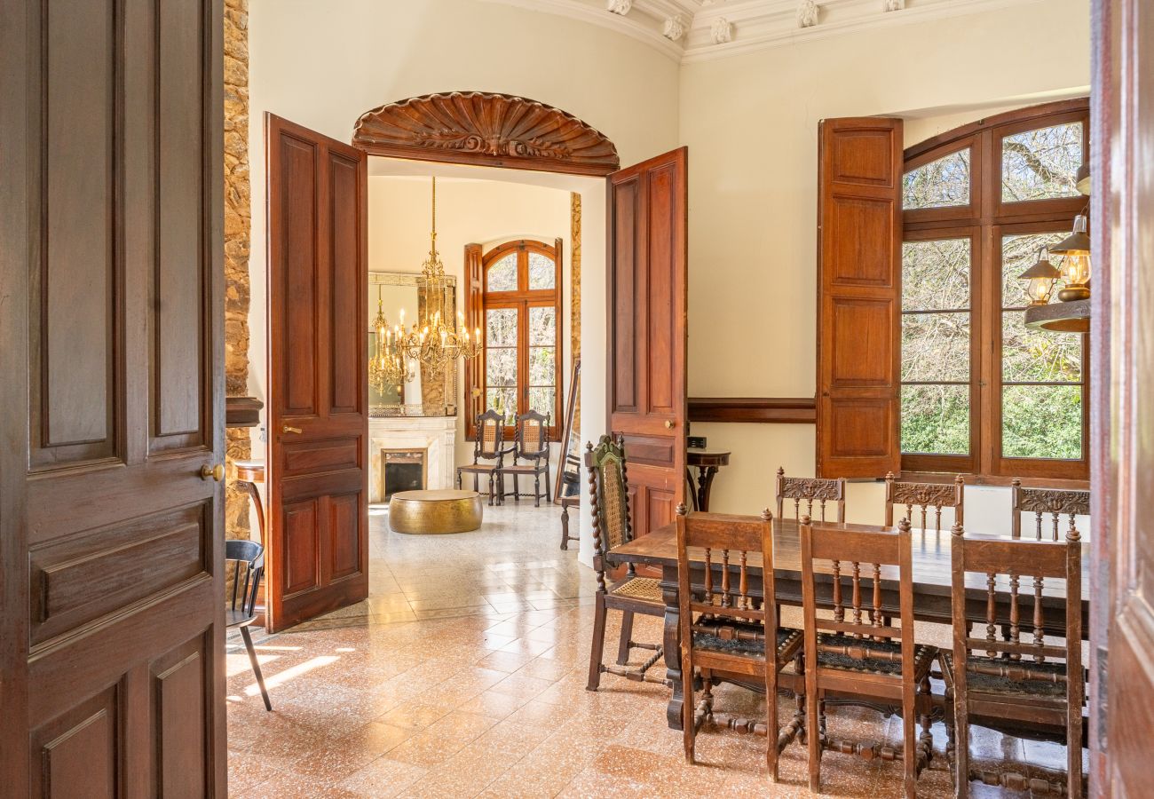 Sala circular en torre con araña de latón, chimenea decorativa de piedra y ventana arqueada en un castillo de Girona